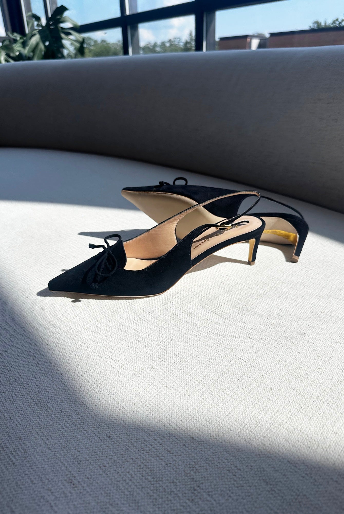 Black high-heeled shoes on a light surface with a blurred outdoor background