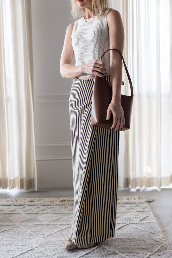 image of a woman wearing the Sablyn Aja Tank and Alysi Striped Skirt with the Aesther Ekme Demi Lune Bag