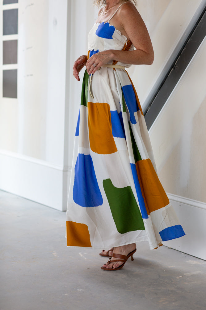 Woman wearing a colorful dress with geometric patterns in a minimal indoor setting.