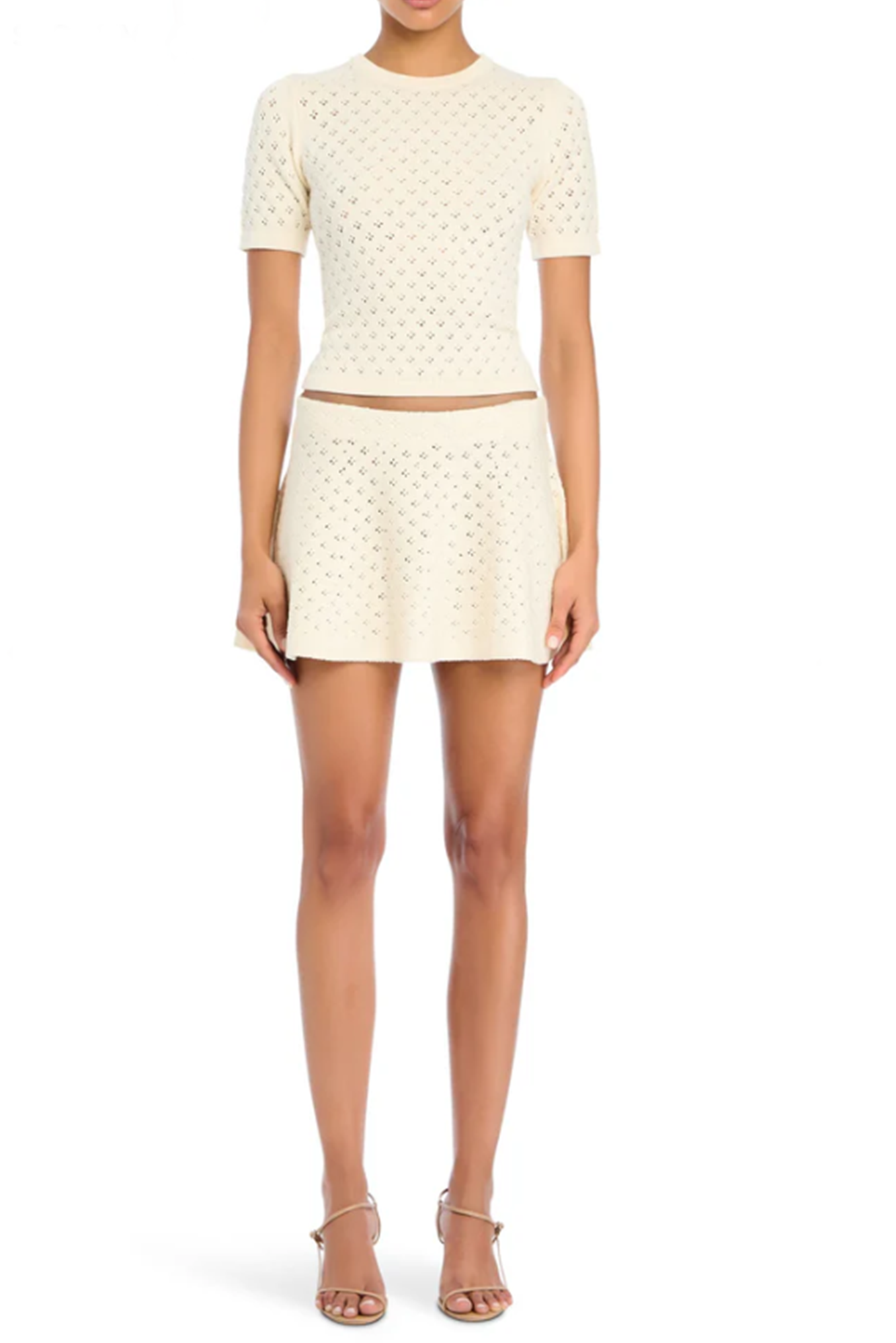 Woman wearing a eggshell knit top and skirt set on a white background