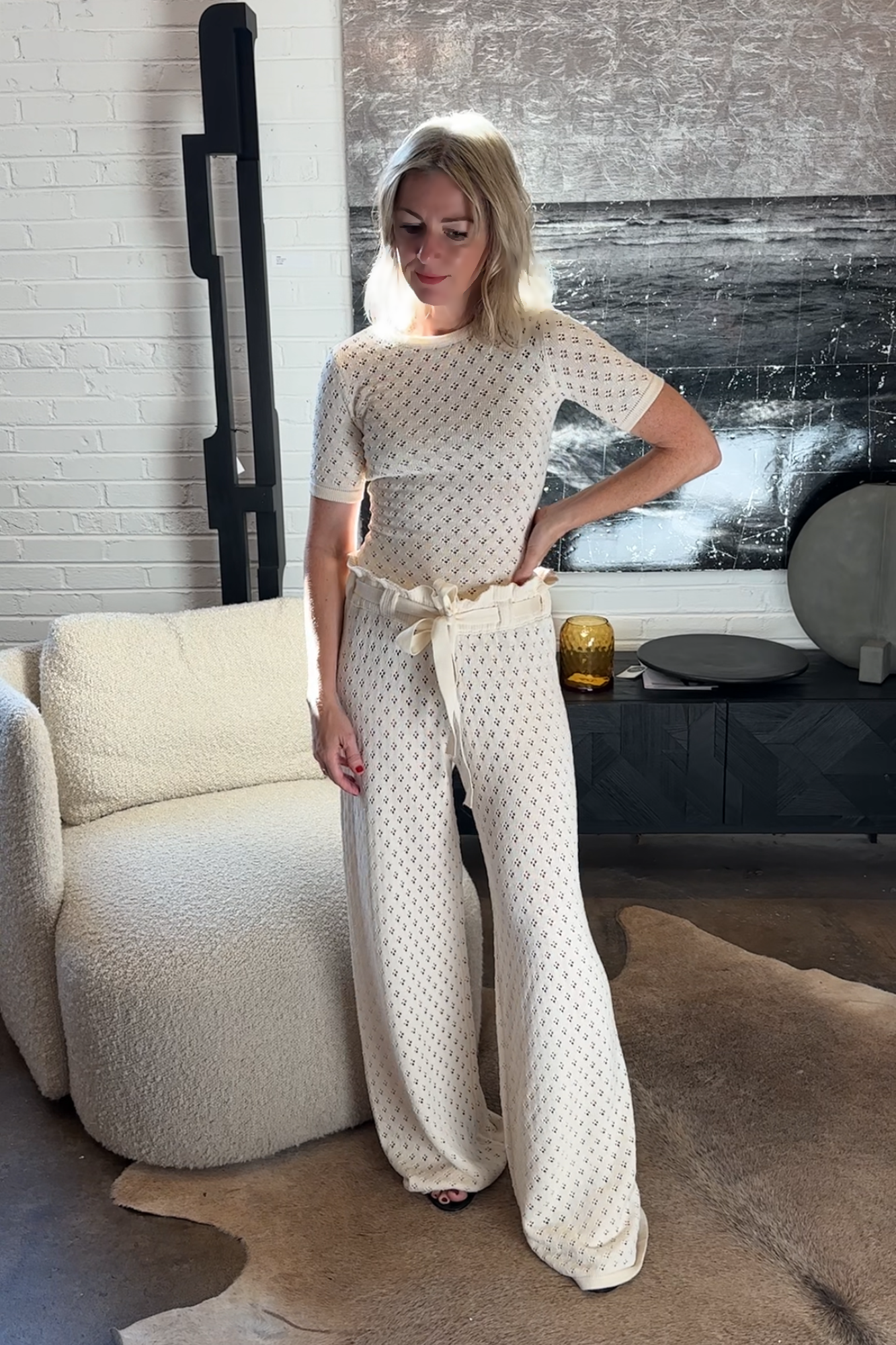 Woman in a knit outfit standing in a modern living room.