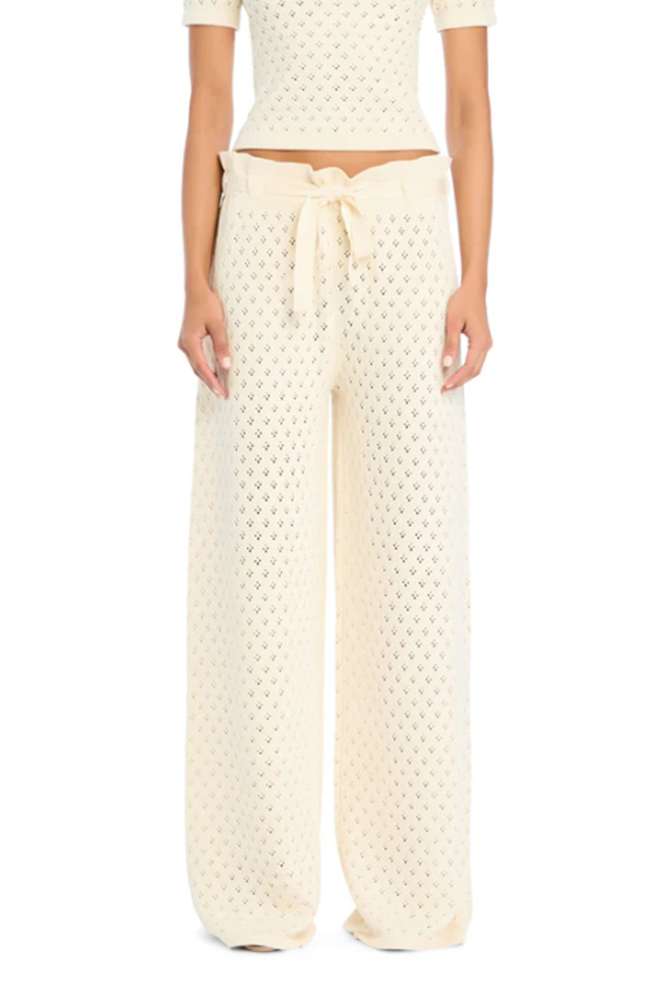 Person wearing a white knit textured top and wide-leg pants on a white background