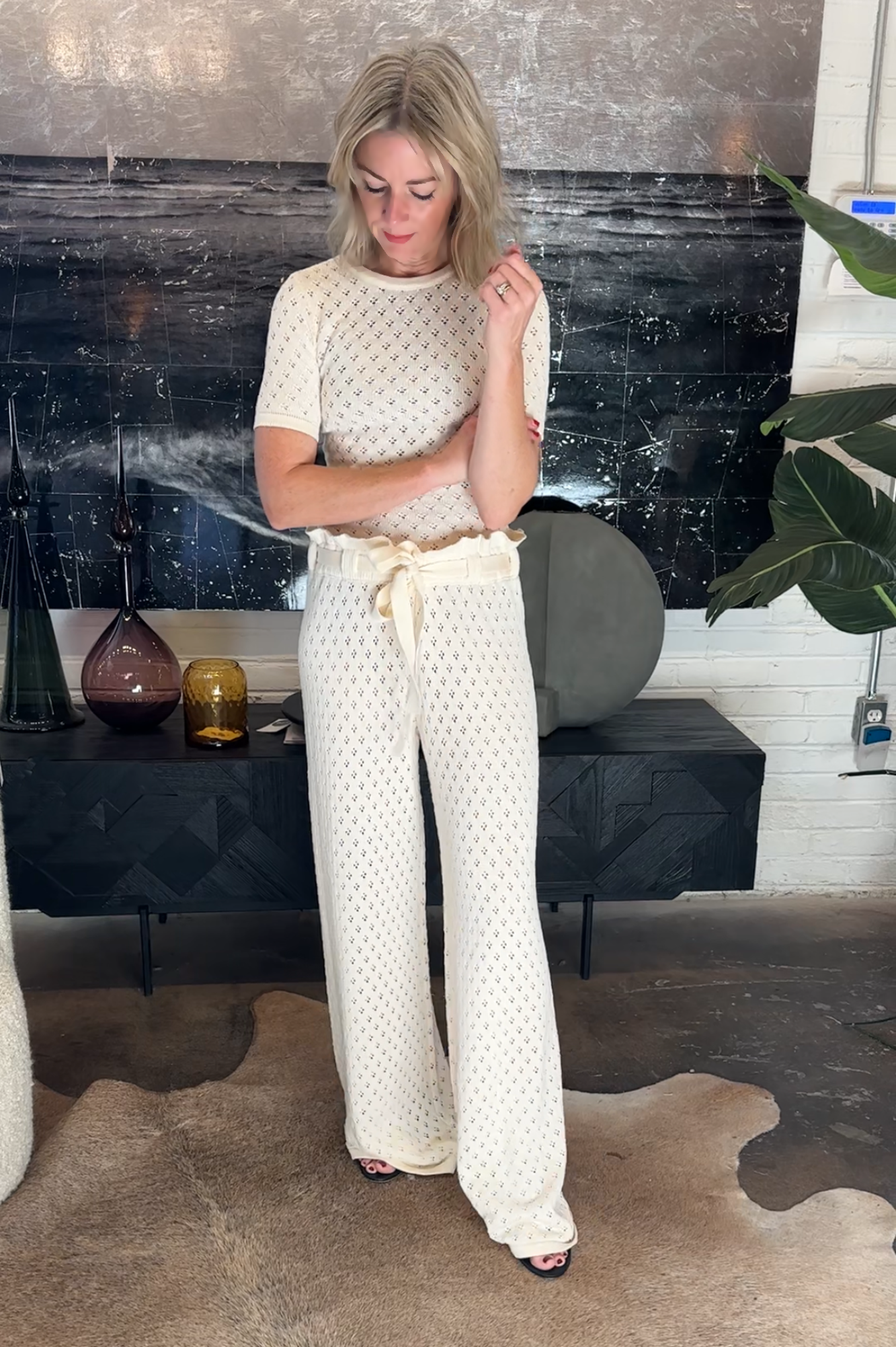 Woman in a white knit outfit standing in a room with decorative elements.
