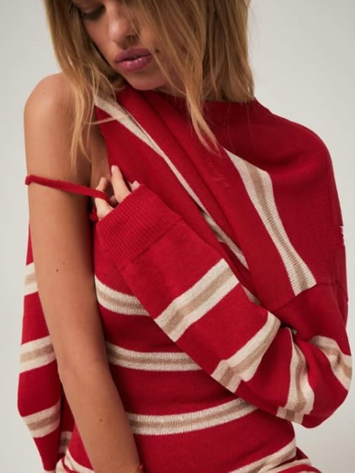 Woman wearing a red and beige striped sweater against a white background