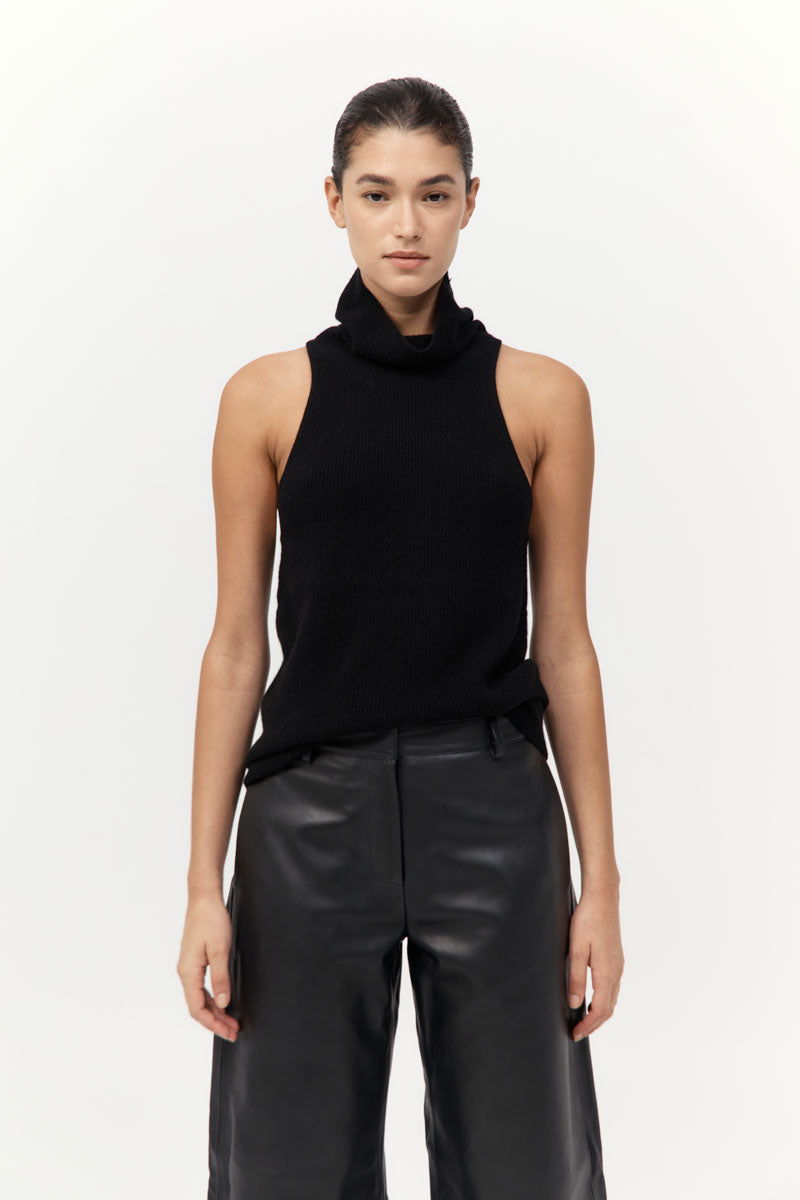 Woman wearing a black sleeveless top and leather pants on a white background