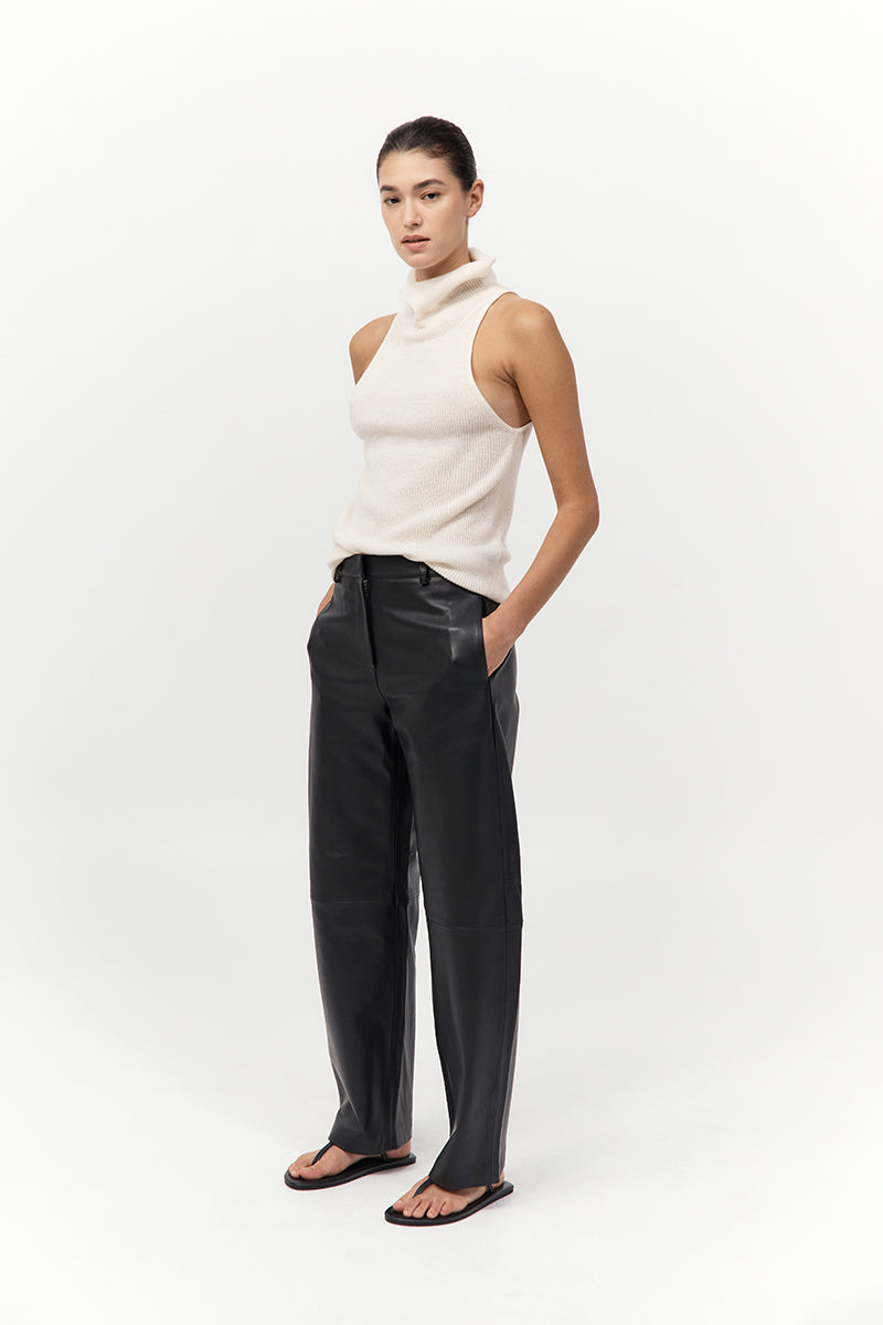 Woman wearing a white sleeveless top and black pants on a white background