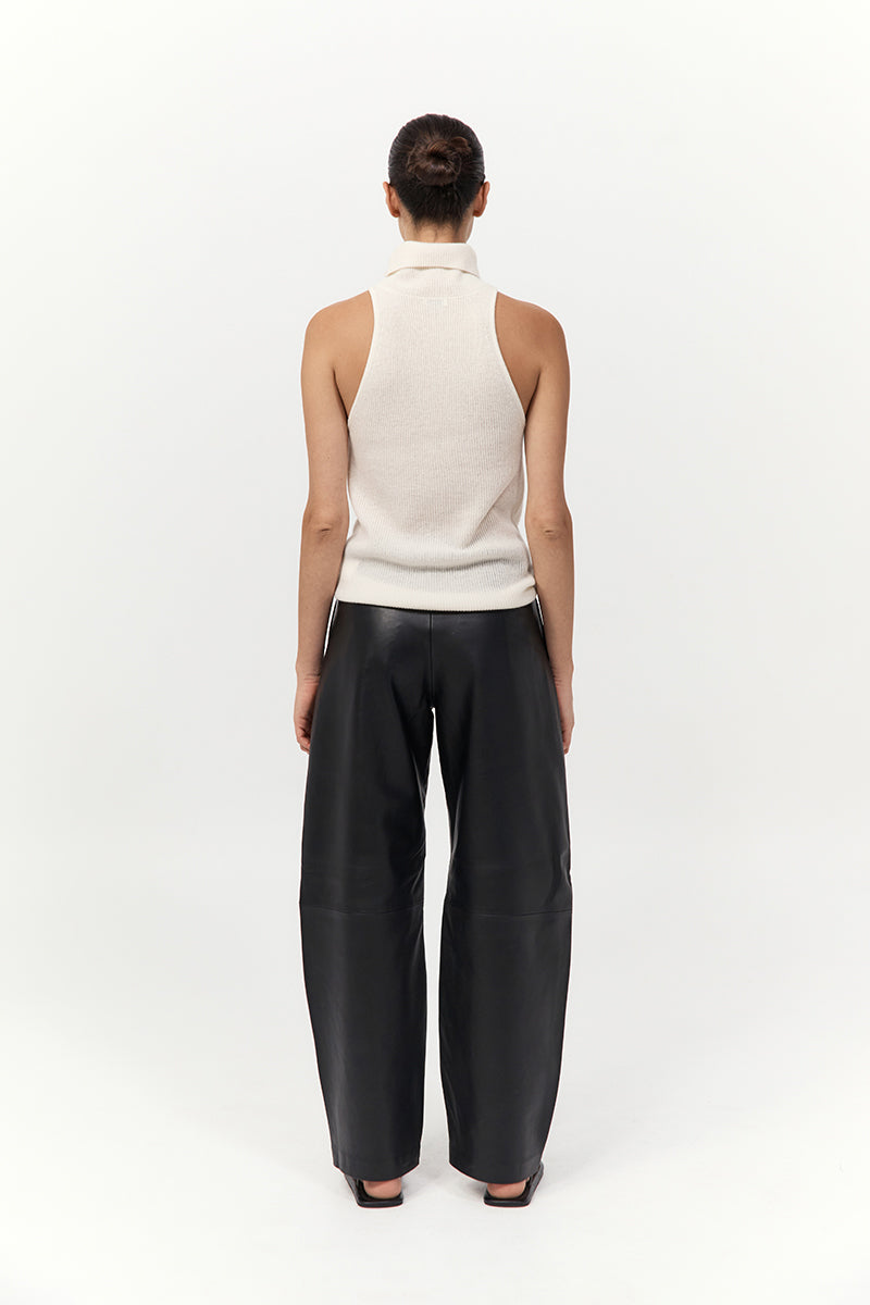 Person wearing a white sleeveless top and black pants on a white background