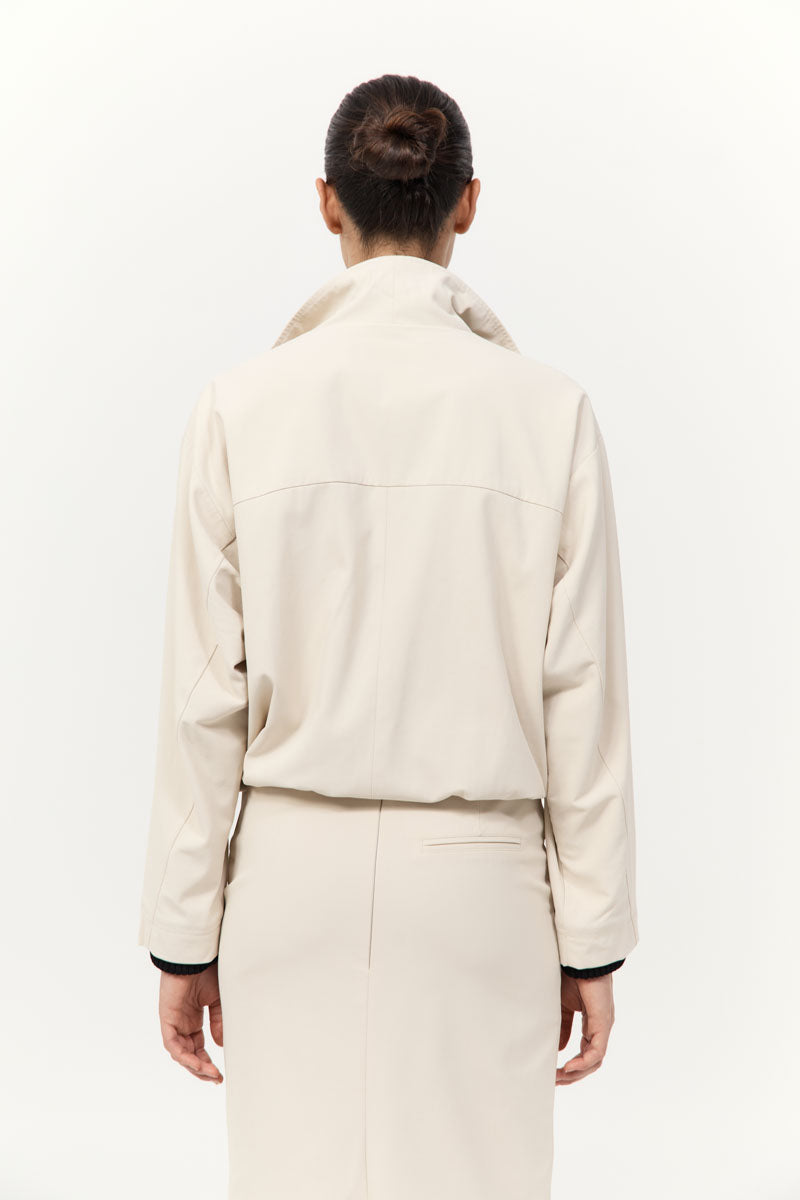 Person wearing a beige jacket and pants on a white background