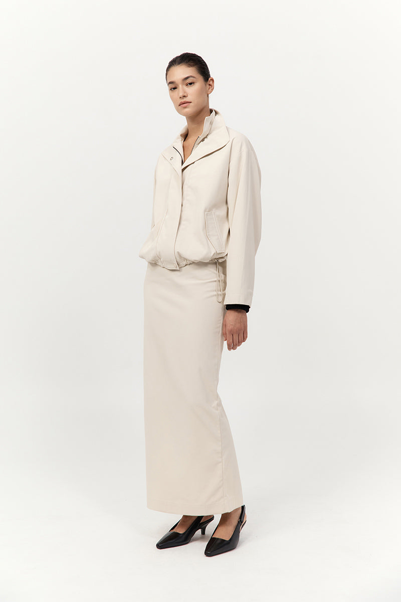 Person wearing a beige outfit with a jacket and pants on a white background