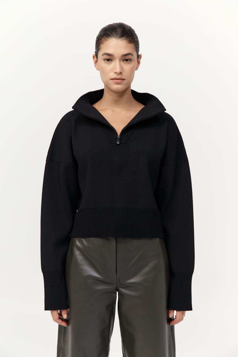Person wearing a black hoodie and gray pants on a white background