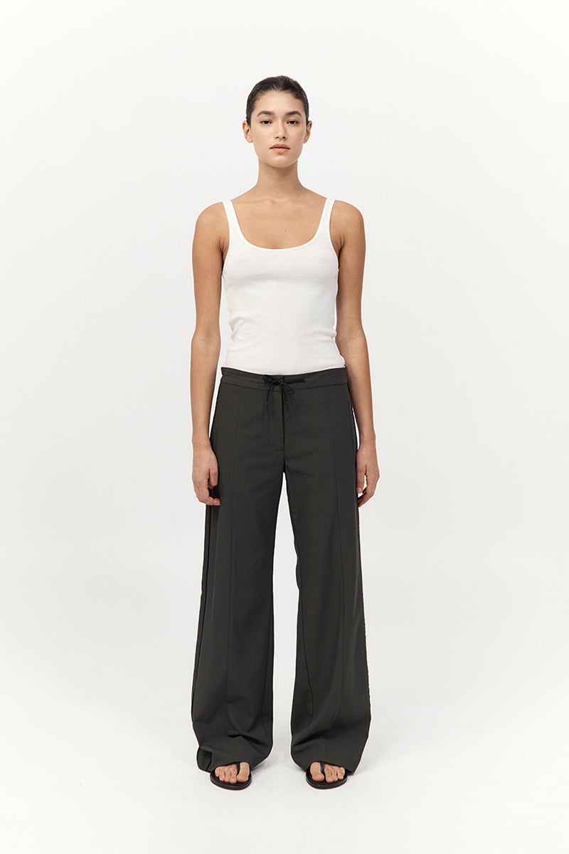 Woman wearing a white tank top and black pants on a white background