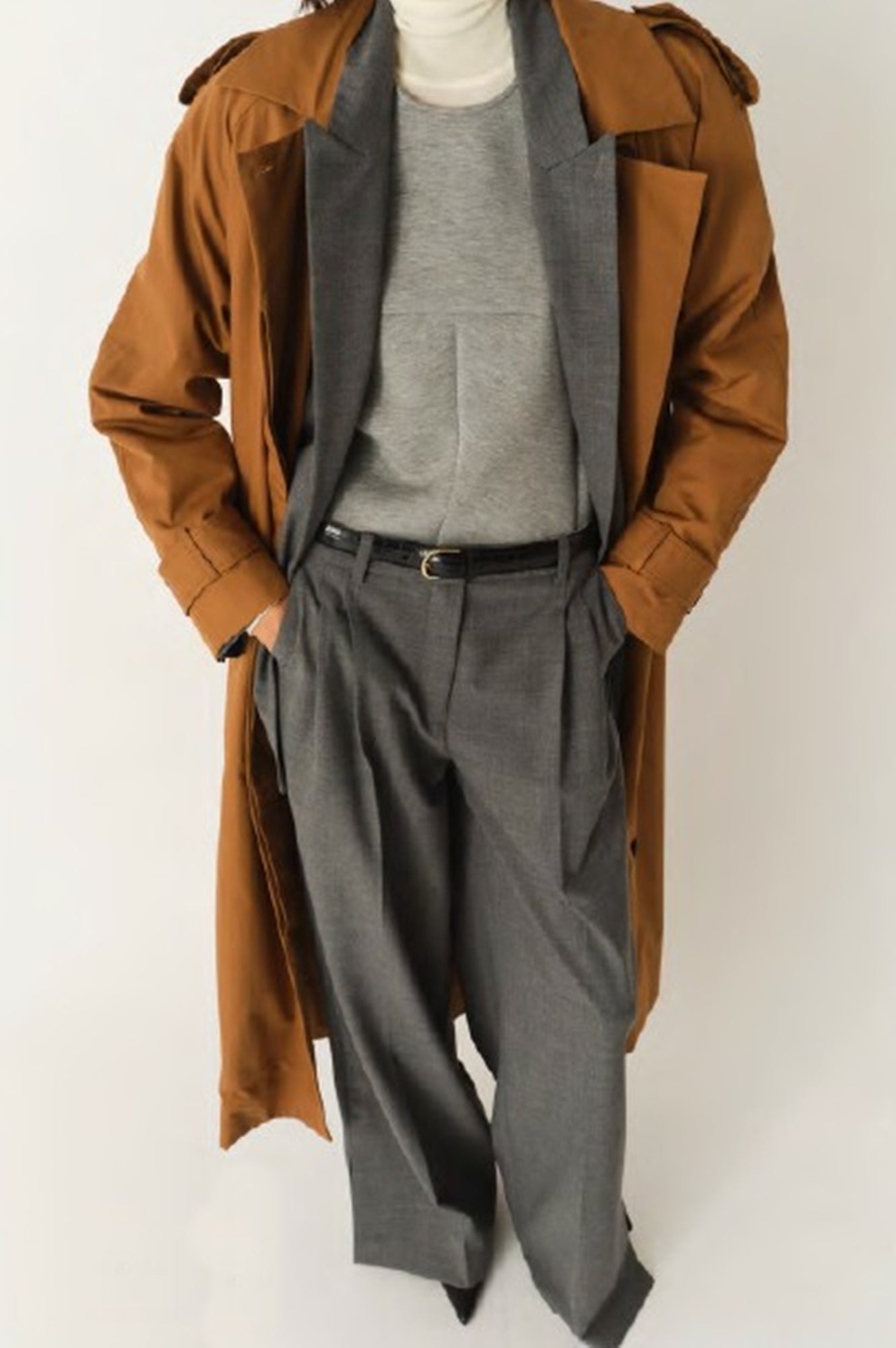 Mannequin wearing a brown trench coat over a gray outfit on a white background