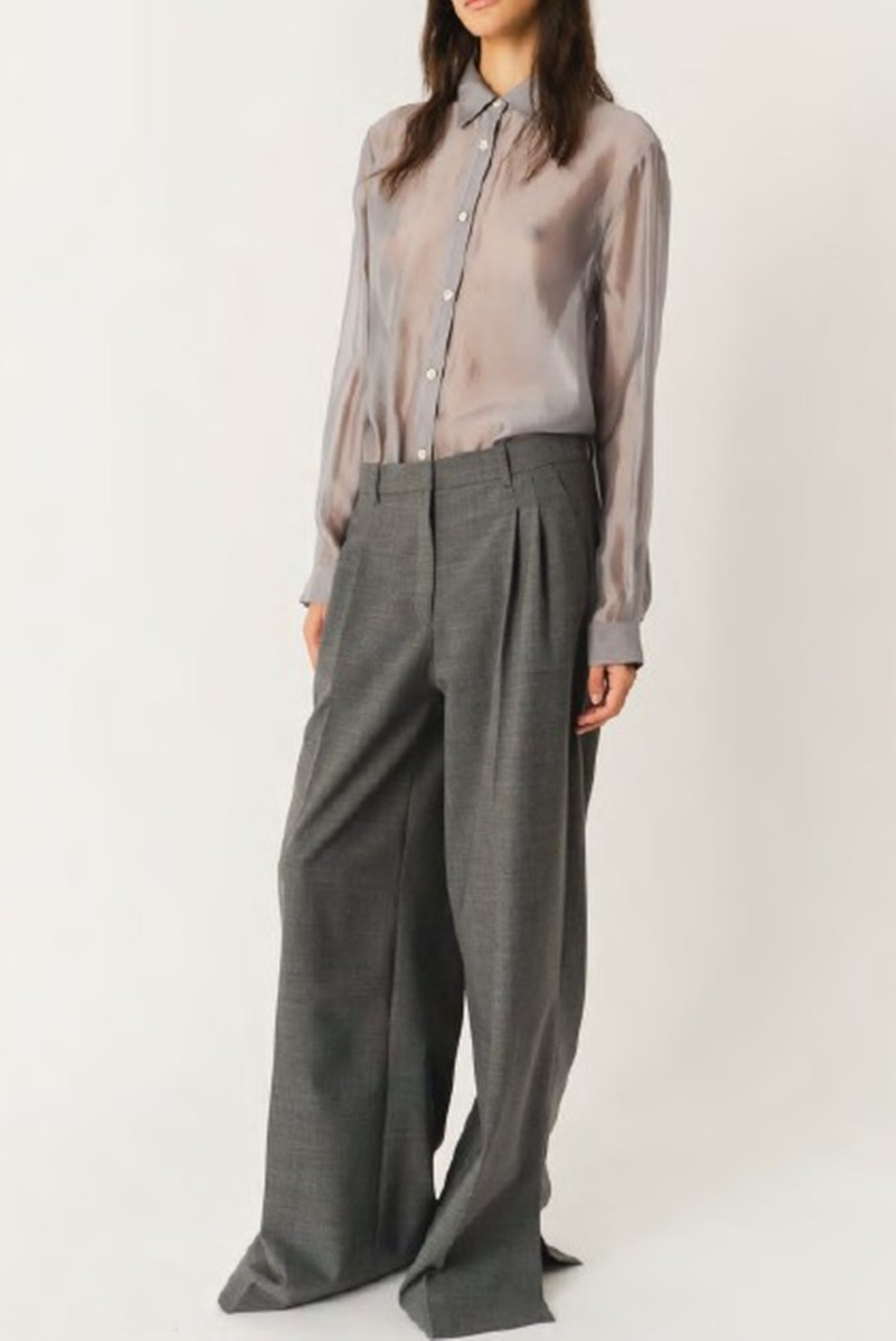 Person wearing a light gray shirt and dark gray wide-leg pants on a white background