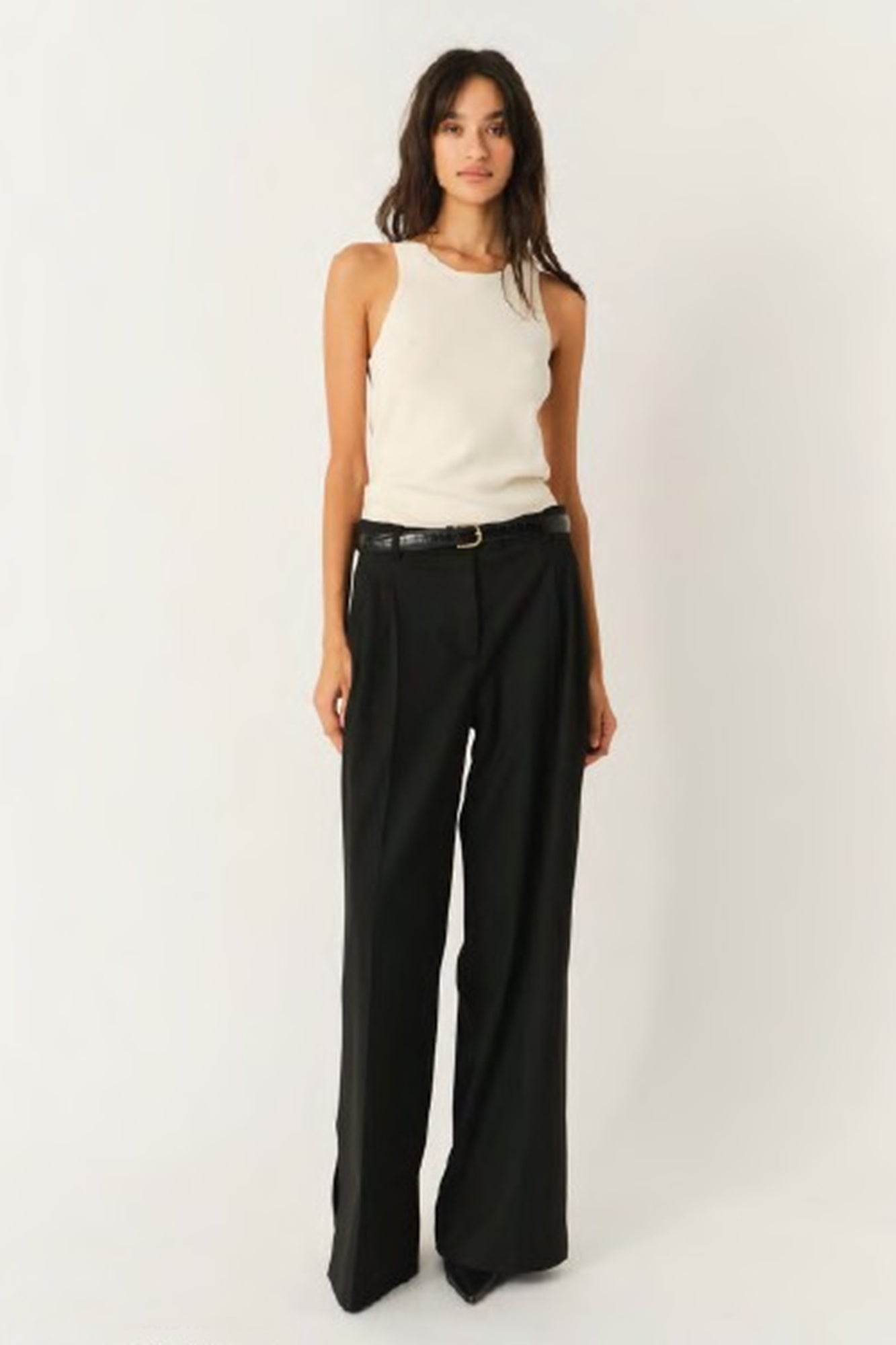 Woman wearing a white sleeveless top and black wide-leg pants on a white background