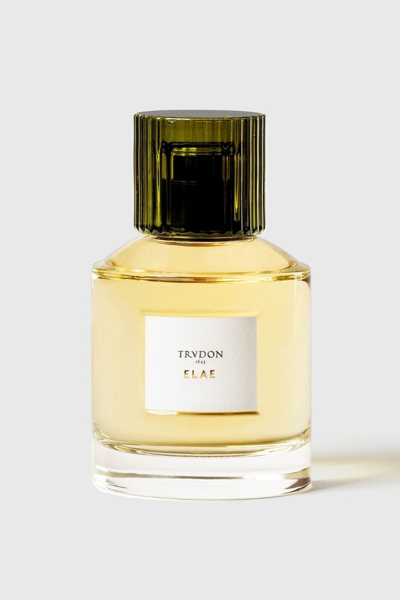 Perfume bottle with green cap and white label on a light gray background